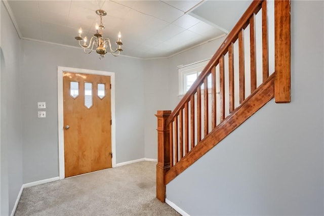 carpeted entrance foyer featuring crown molding and an inviting chandelier