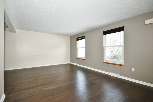 spare room featuring a textured ceiling and dark hardwood / wood-style flooring