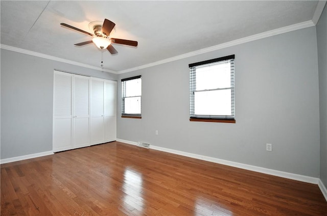 unfurnished bedroom featuring hardwood / wood-style flooring, ornamental molding, and a closet