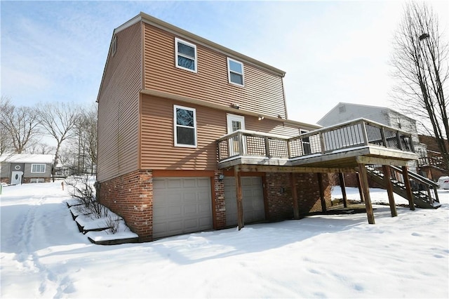 snow covered house featuring a garage and a deck