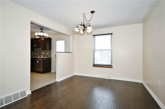 unfurnished dining area with a notable chandelier, hardwood / wood-style flooring, and a wealth of natural light