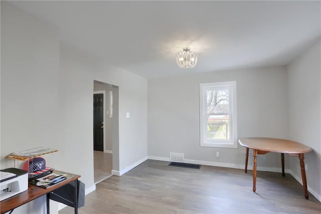 spare room with a notable chandelier and wood-type flooring