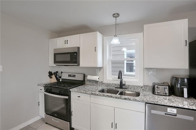 kitchen featuring decorative light fixtures, white cabinetry, sink, stainless steel appliances, and light stone countertops