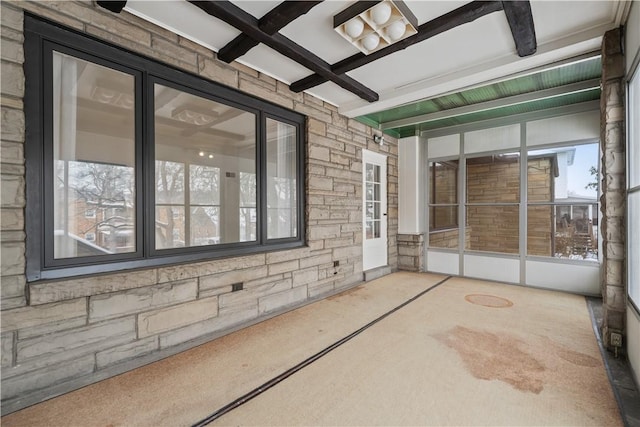 unfurnished sunroom featuring beamed ceiling