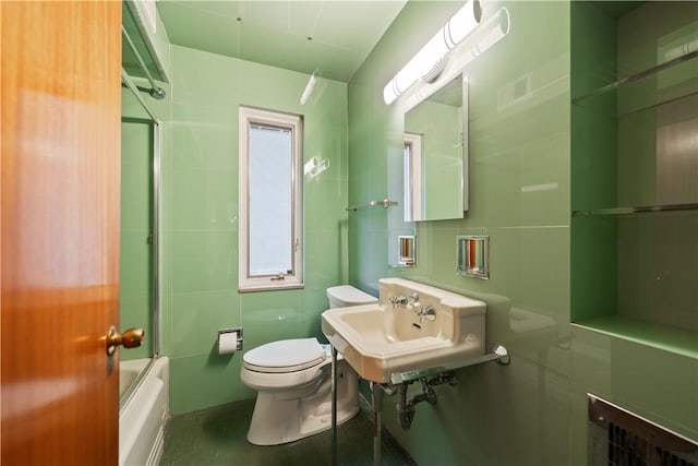 full bathroom featuring toilet, bath / shower combo with glass door, and sink