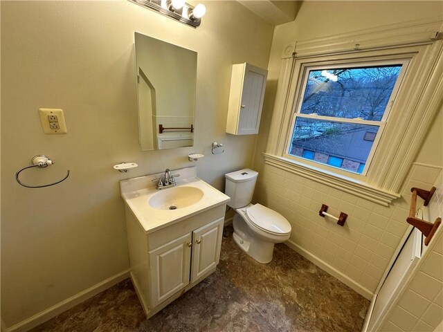 bathroom with vanity, toilet, and tile walls