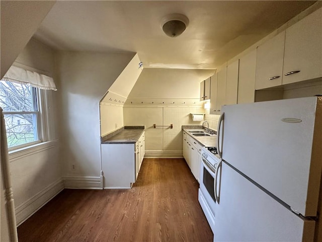 kitchen with white appliances, dark hardwood / wood-style flooring, sink, and white cabinets