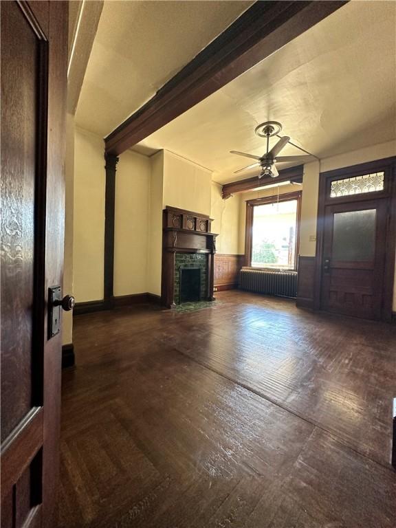 unfurnished living room featuring beamed ceiling, radiator heating unit, and ceiling fan