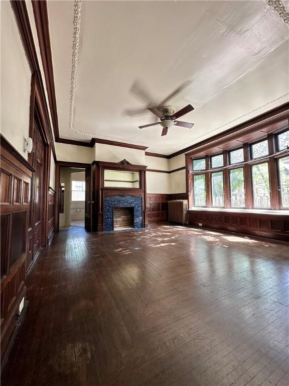 unfurnished living room with ornamental molding, plenty of natural light, radiator, and a tile fireplace