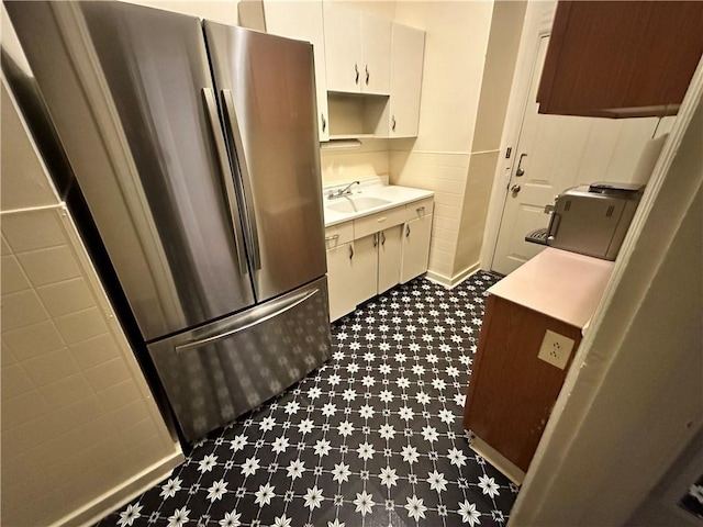 kitchen featuring white cabinetry, stainless steel fridge, and sink