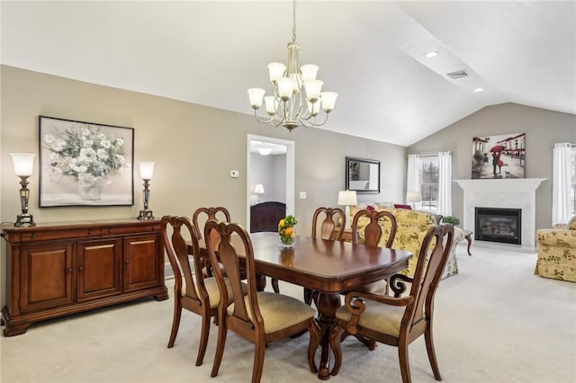 dining space featuring a chandelier, vaulted ceiling, and light carpet