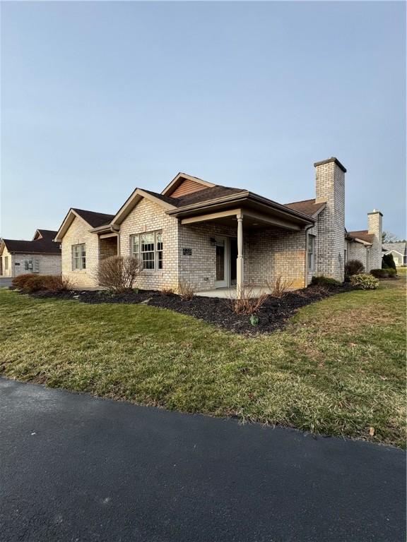 single story home with brick siding, a chimney, and a front lawn