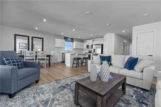 living room featuring sink and light hardwood / wood-style floors