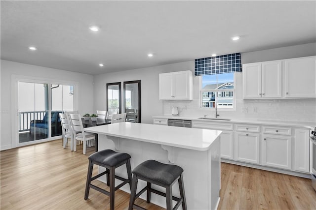 kitchen featuring a center island, stainless steel dishwasher, white cabinets, and light hardwood / wood-style flooring