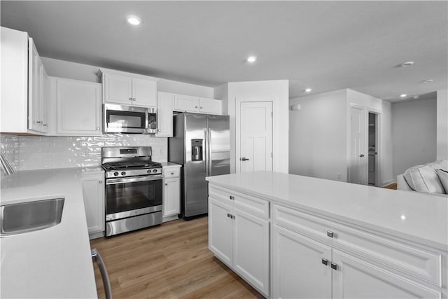 kitchen with white cabinetry, sink, decorative backsplash, light hardwood / wood-style floors, and stainless steel appliances