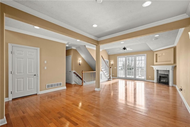 unfurnished living room featuring ornamental molding, light wood-type flooring, ceiling fan, and a fireplace