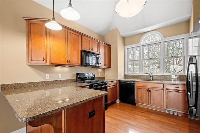 kitchen featuring sink, black appliances, decorative light fixtures, vaulted ceiling, and kitchen peninsula