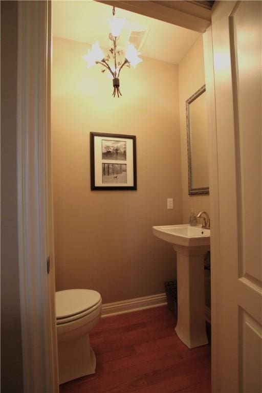 bathroom with an inviting chandelier, hardwood / wood-style floors, and toilet