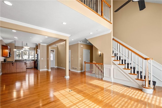 unfurnished living room featuring a high ceiling, ceiling fan, and light wood-type flooring