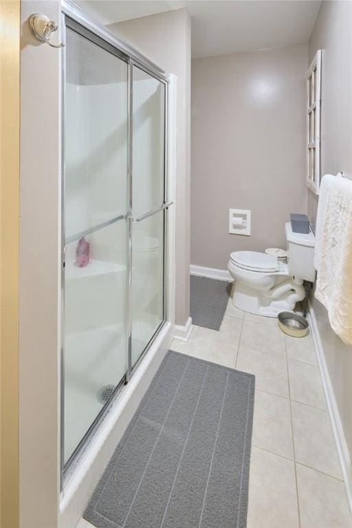 bathroom with a shower with door, tile patterned floors, and toilet