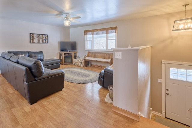 living room featuring ceiling fan with notable chandelier and light hardwood / wood-style floors