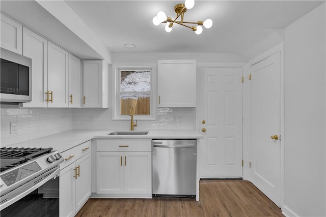 kitchen featuring stainless steel appliances, sink, white cabinets, and light hardwood / wood-style flooring