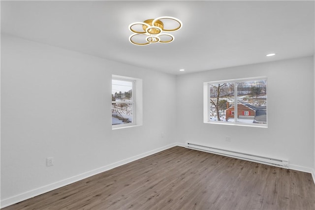 empty room featuring wood-type flooring and a baseboard heating unit