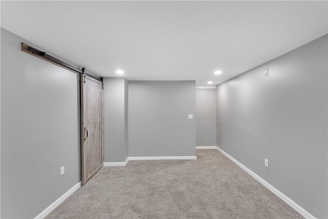 basement with light colored carpet and a barn door