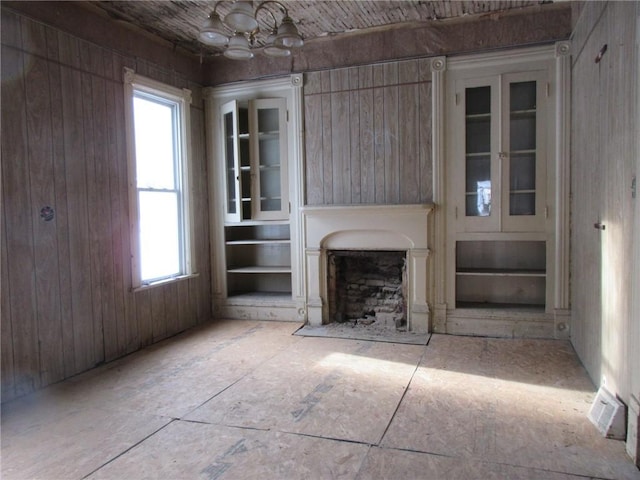 unfurnished living room with wooden walls and a chandelier