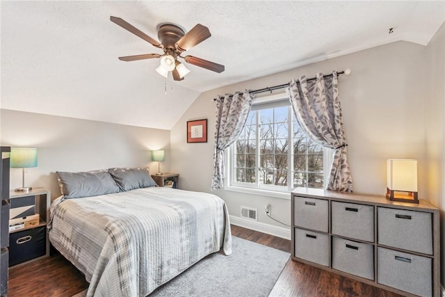 bedroom with lofted ceiling, dark wood-type flooring, and a textured ceiling