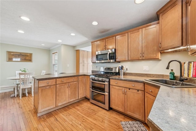 kitchen with sink, light hardwood / wood-style flooring, kitchen peninsula, and appliances with stainless steel finishes