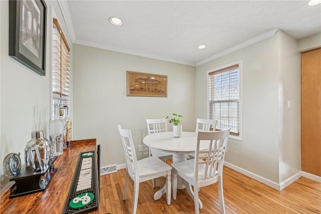 dining area featuring crown molding and light hardwood / wood-style flooring