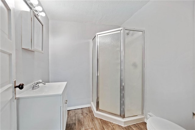 bathroom with vanity, hardwood / wood-style floors, a shower with door, and a textured ceiling