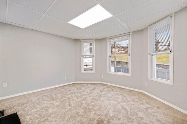 carpeted empty room with a paneled ceiling