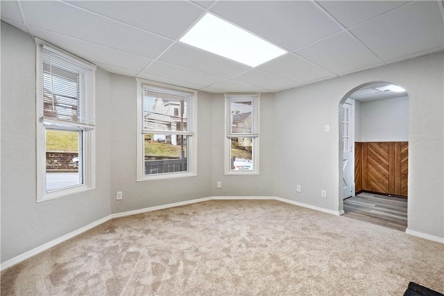 spare room featuring a paneled ceiling and light carpet