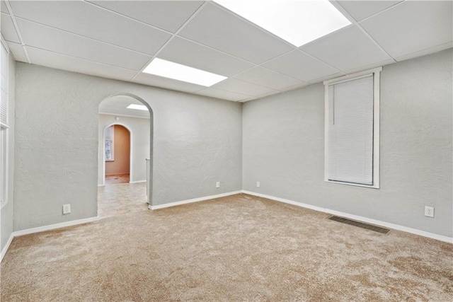 empty room with carpet flooring and a drop ceiling