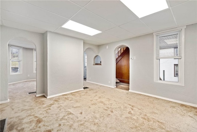 carpeted empty room with a drop ceiling