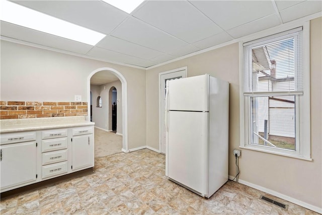 kitchen with a drop ceiling, white cabinets, and white fridge