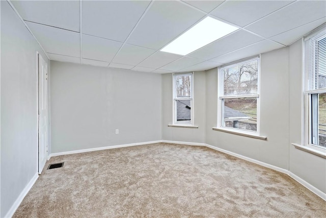 spare room with a paneled ceiling and light carpet