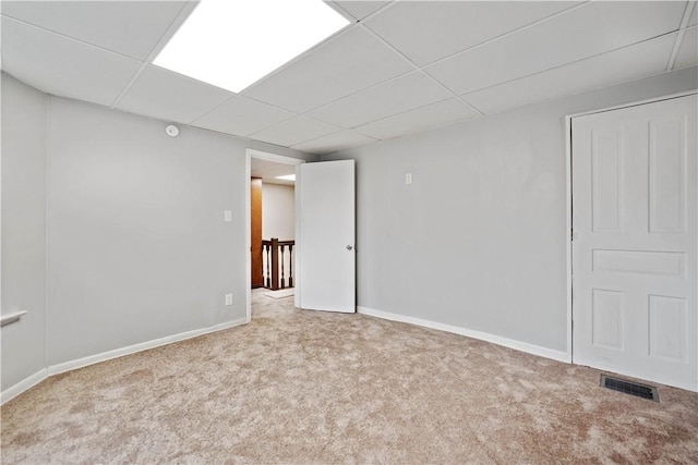 carpeted empty room with a drop ceiling