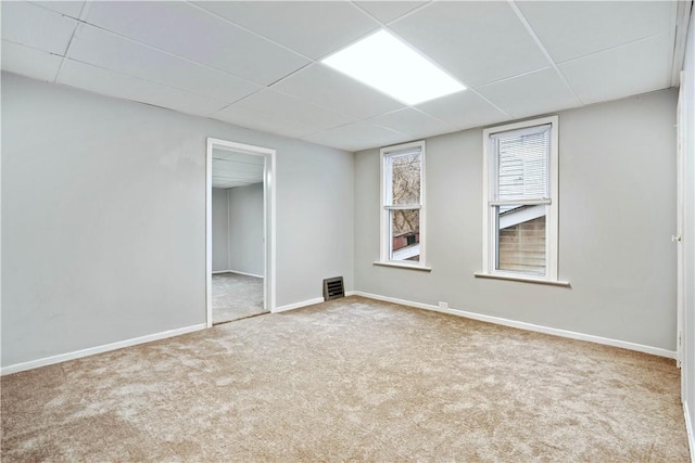 carpeted spare room with a drop ceiling