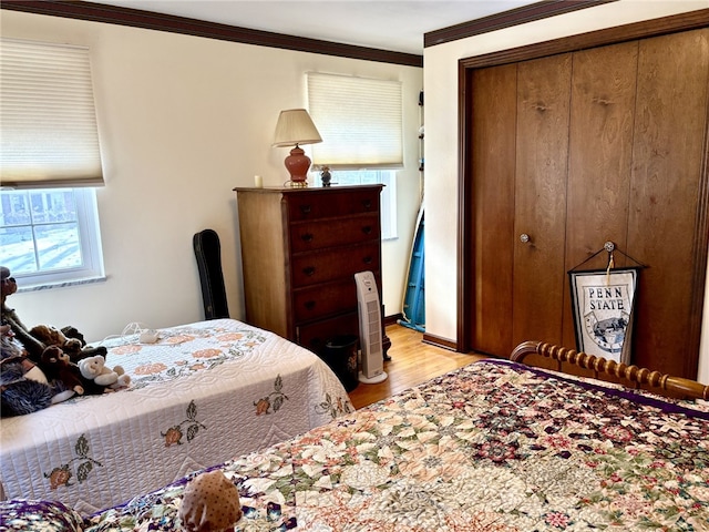 bedroom featuring ornamental molding, light wood-type flooring, and a closet