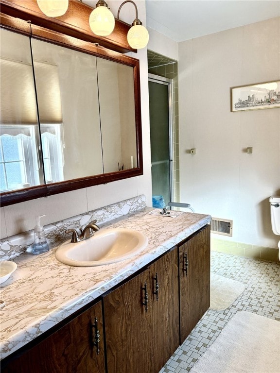 bathroom featuring a shower with door, vanity, and tile patterned floors