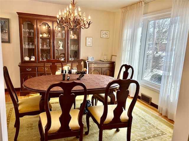 dining room featuring baseboards, visible vents, and a chandelier