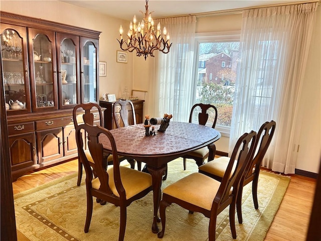 dining area with light wood-style floors and a notable chandelier