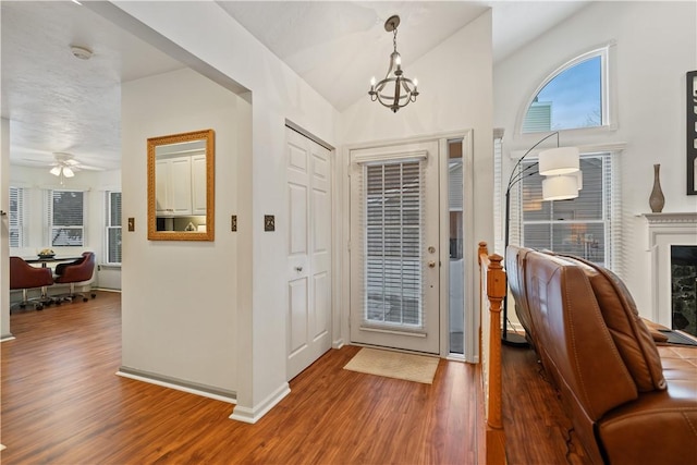 entryway with an inviting chandelier, hardwood / wood-style floors, and vaulted ceiling