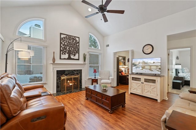 living room featuring wood-type flooring, high vaulted ceiling, ceiling fan, and a high end fireplace