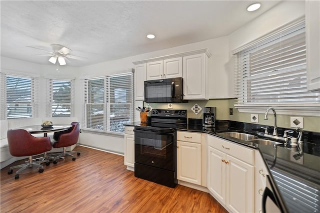 kitchen with sink, white cabinets, ceiling fan, black appliances, and light hardwood / wood-style flooring