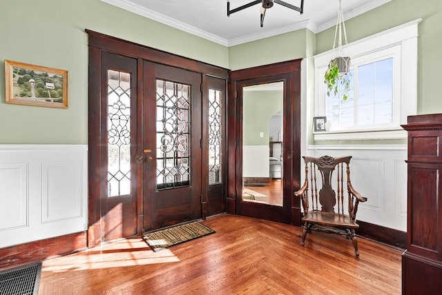 foyer with crown molding, french doors, and light parquet floors