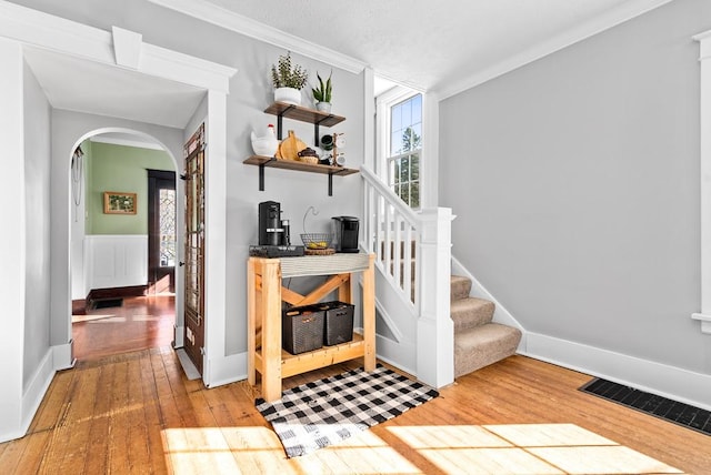 staircase with wood-type flooring and crown molding